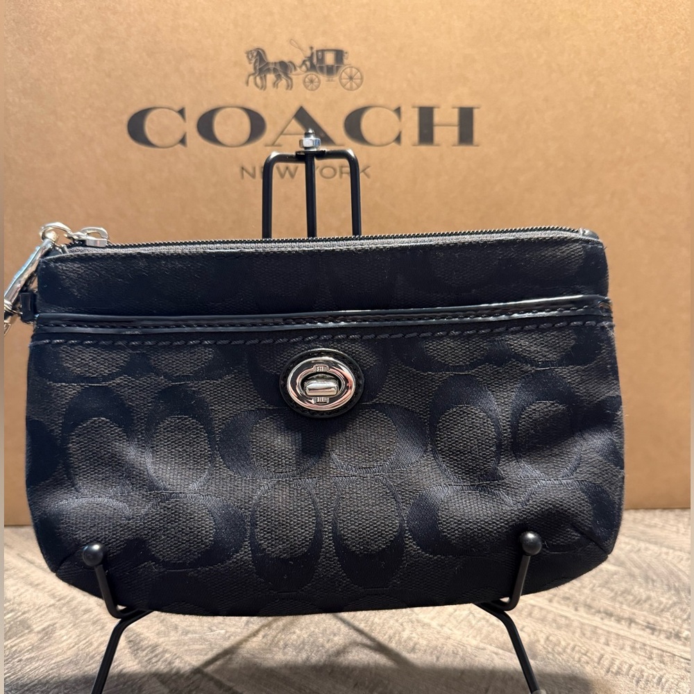 Black Jacquard Coach Signature
Turnlock Wristlet with Silver Hardware.
